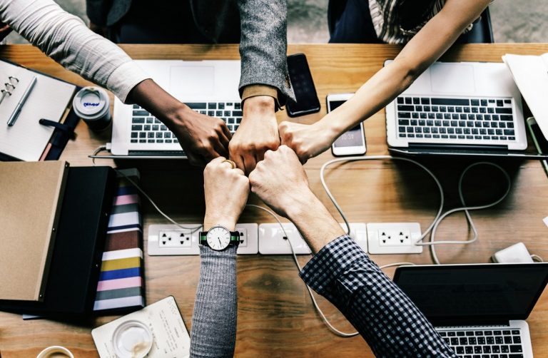 A team of marketers fist bumping during a collaborative SEO meeting